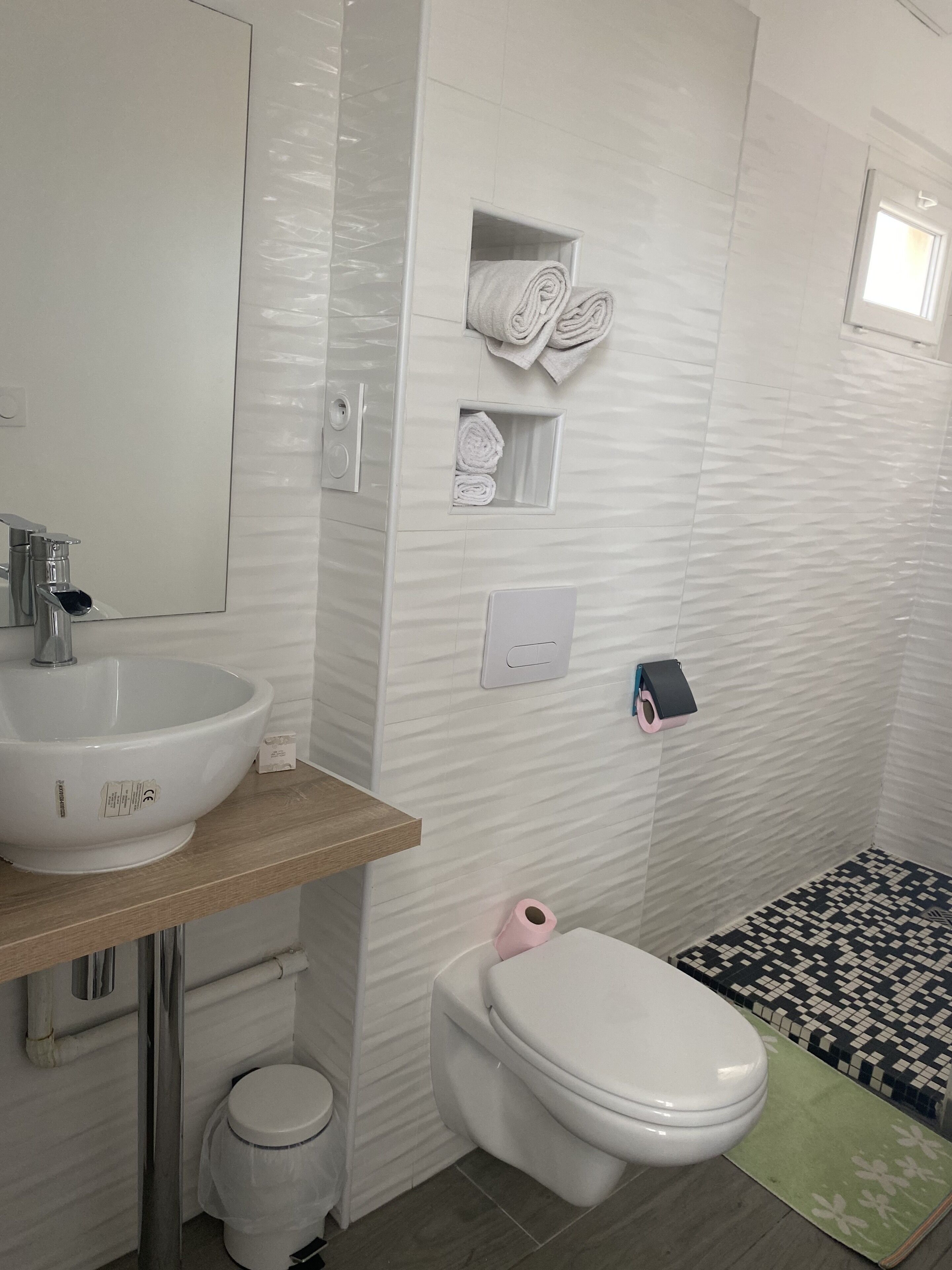 A bathroom with a white sink, toilet, and towel storage.