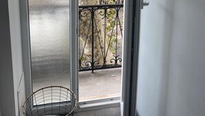 Vista a través de un vidrio con barandilla de metal, un árbol y una silla afuera.