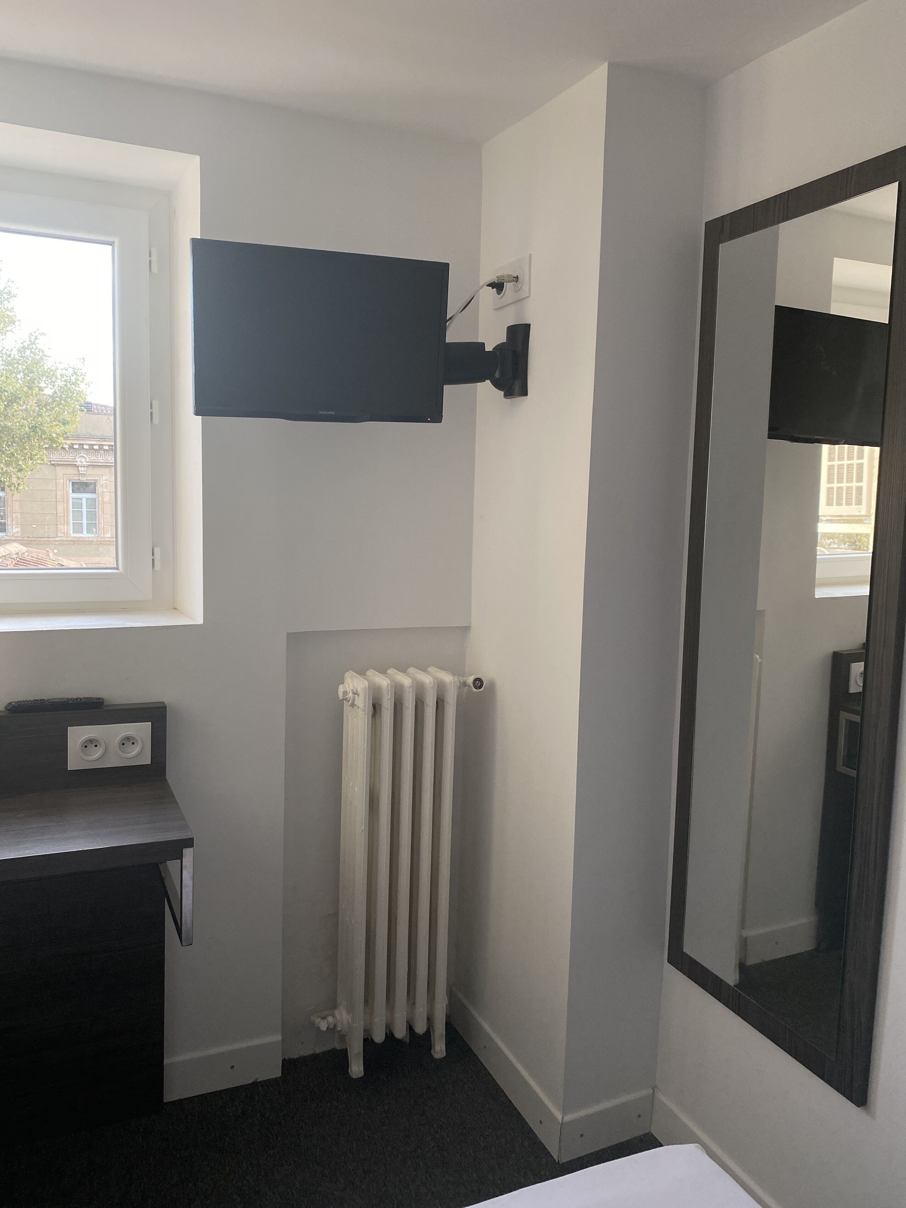 A bathroom with a white radiator, a mirror, and a window.