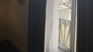 Una habitación con ventana, aire acondicionado de pared y dos adornos colgantes.
