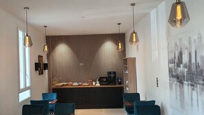 Una cocina moderna con una isla central, iluminación colgante y una obra de arte con vista a la ciudad.