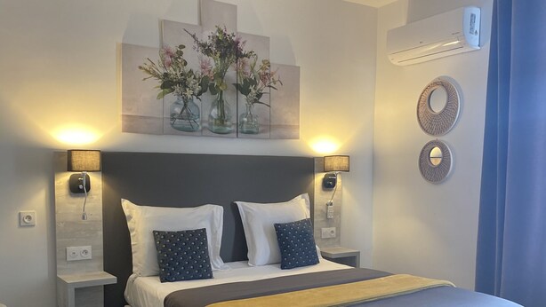 Un dormitorio moderno con una cama grande, dos mesitas de noche, lámparas fijadas a la pared y un adorno decorativo sobre la cama.