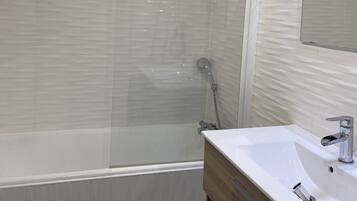 A modern bathroom with a bathtub, a sink, and a glass-enclosed shower.