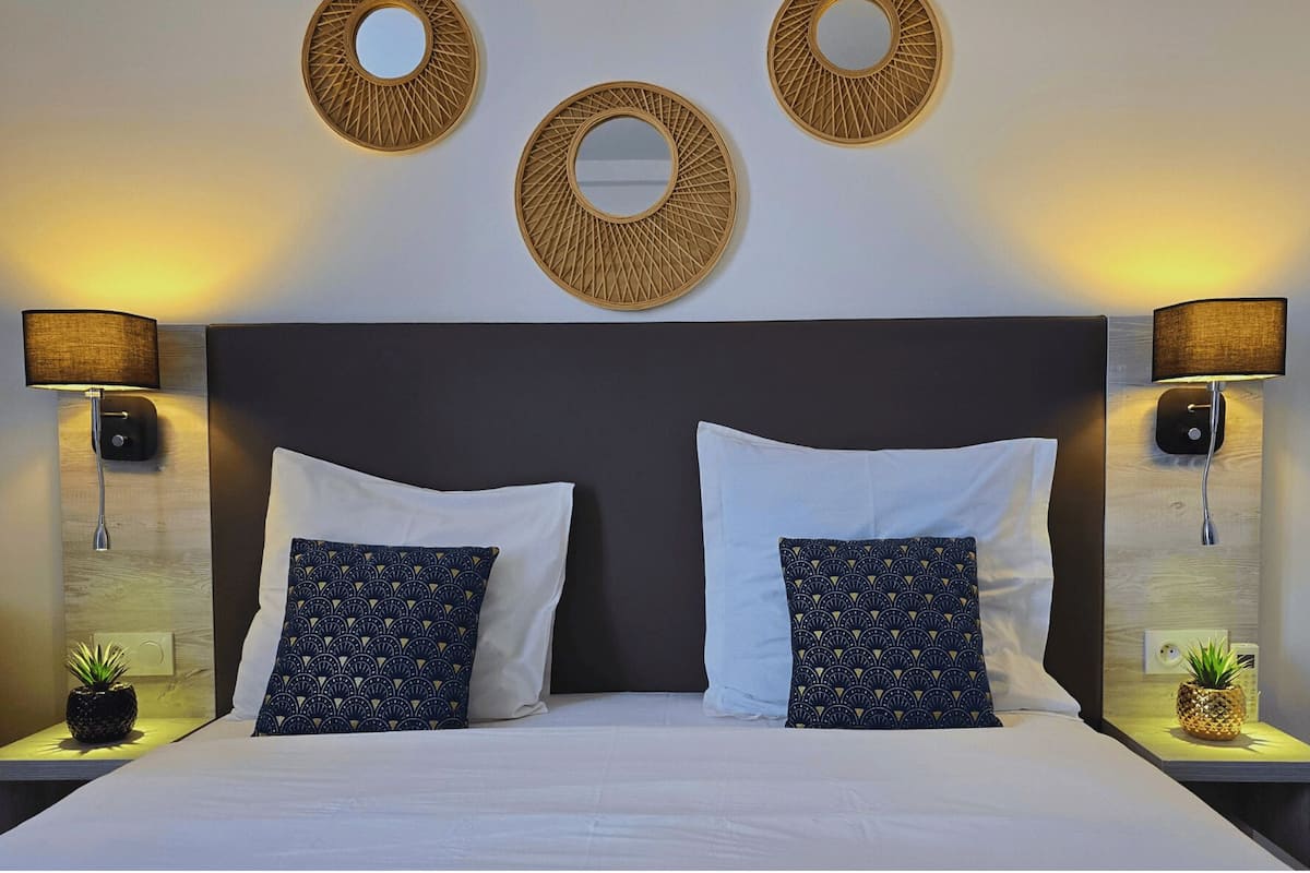 A hotel room with a large bed, two nightstands, two wall-mounted lamps, and three circular wall decorations.