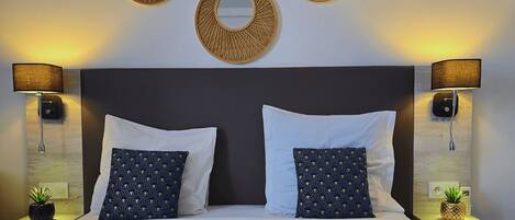 Habitación de hotel con una cama grande, dos mesitas de noche, dos lámparas de pared y tres adornos circulares en la pared.