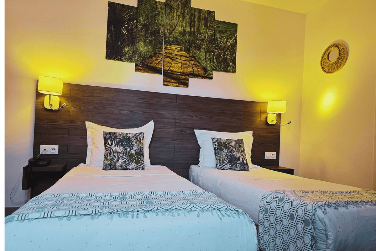 A double bed with patterned bedding, two bedside tables with lamps, a wall-mounted artwork, and a decorative mirror.
