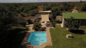 A swimming pool with a sunshade, a staircase, and a view of the surrounding landscape.