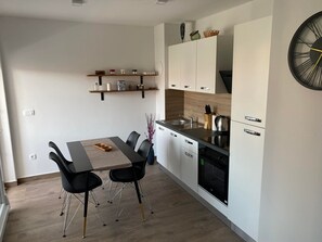 Et moderne køkken med spisebord, stole og integreret hårde hvidevarer.