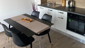 Una cocina moderna con comedor, que incluye una mesa de madera, sillas negras y un horno empotrado.
