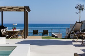 A rooftop terrace with a pool, lounge chairs, and a table with chairs, overlooking the ocean. - Deux Paradis, a BeachFront Retreat with Private Pool & walking distance to all (Rethymno)