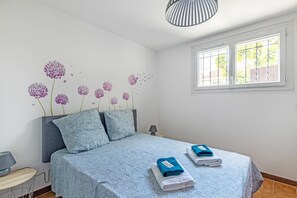 Ett sovrum med en säng, kuddar, en lampa och ett fönster.
