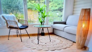 A room with a large window, a round table with a plant, a chair, a sofa, and a tall lamp. - T2 L'orangeraie du Cap d'Antibes (Antibes)
