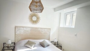 A bedroom with a large bed, a decorative wall hanging, and a window with blinds. - T2 L'orangeraie du Cap d'Antibes (Antibes)