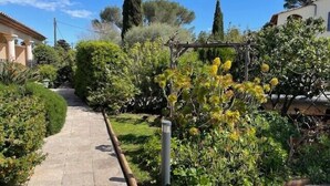A paved pathway leading through a garden with various shrubs and trees. - T2 L'orangeraie du Cap d'Antibes (Antibes)