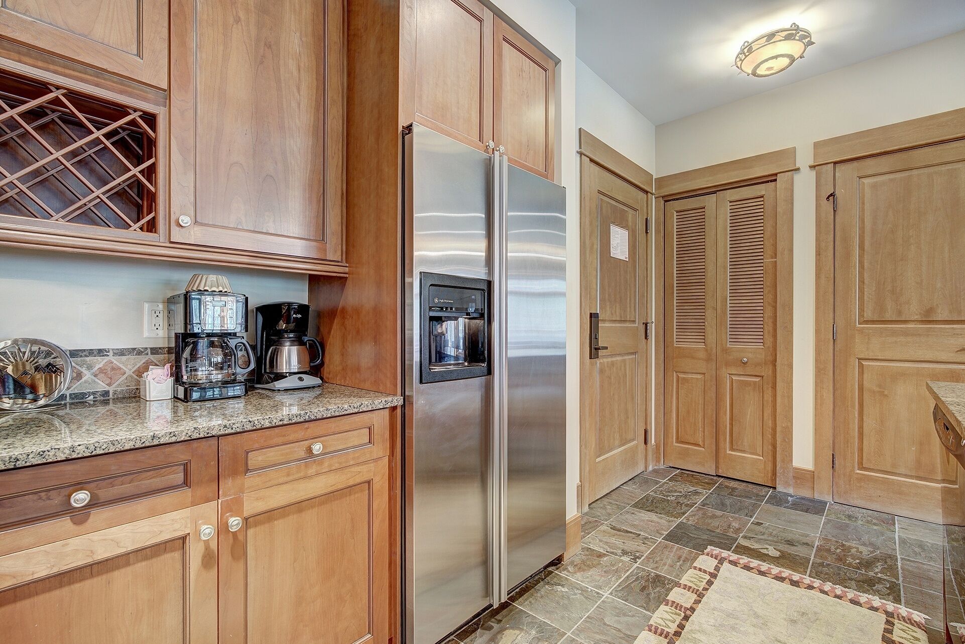 A kitchen with wooden cabinets, a stainless steel refrigerator, a coffee maker, and a water dispenser.