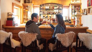A bar area with wooden furniture and a bar counter. There are books and bottles on shelves. - Luxurious 2 Br In River Run Village With Ski In Ski Out, No Cleaning Fees, Kids Ski Free 2 Bedroom Condo by RedAwning (Keystone)