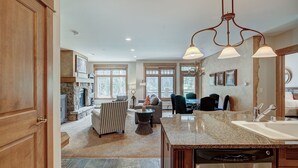 A spacious living area with a fireplace, a dining table, and a kitchen with granite countertops. - Luxurious 2 Br In River Run Village With Ski In Ski Out, No Cleaning Fees, Kids Ski Free 2 Bedroom Condo by RedAwning (Keystone)
