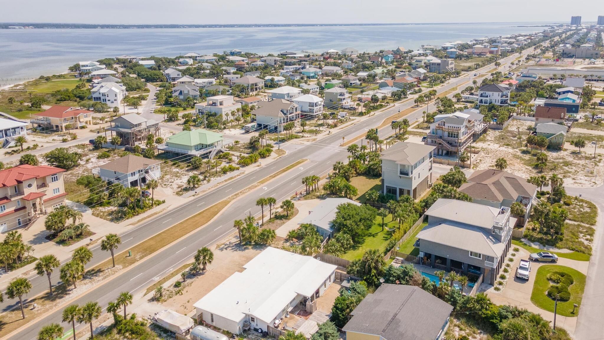 An aerial view of a coastal residential area with houses, roads, and a beach.