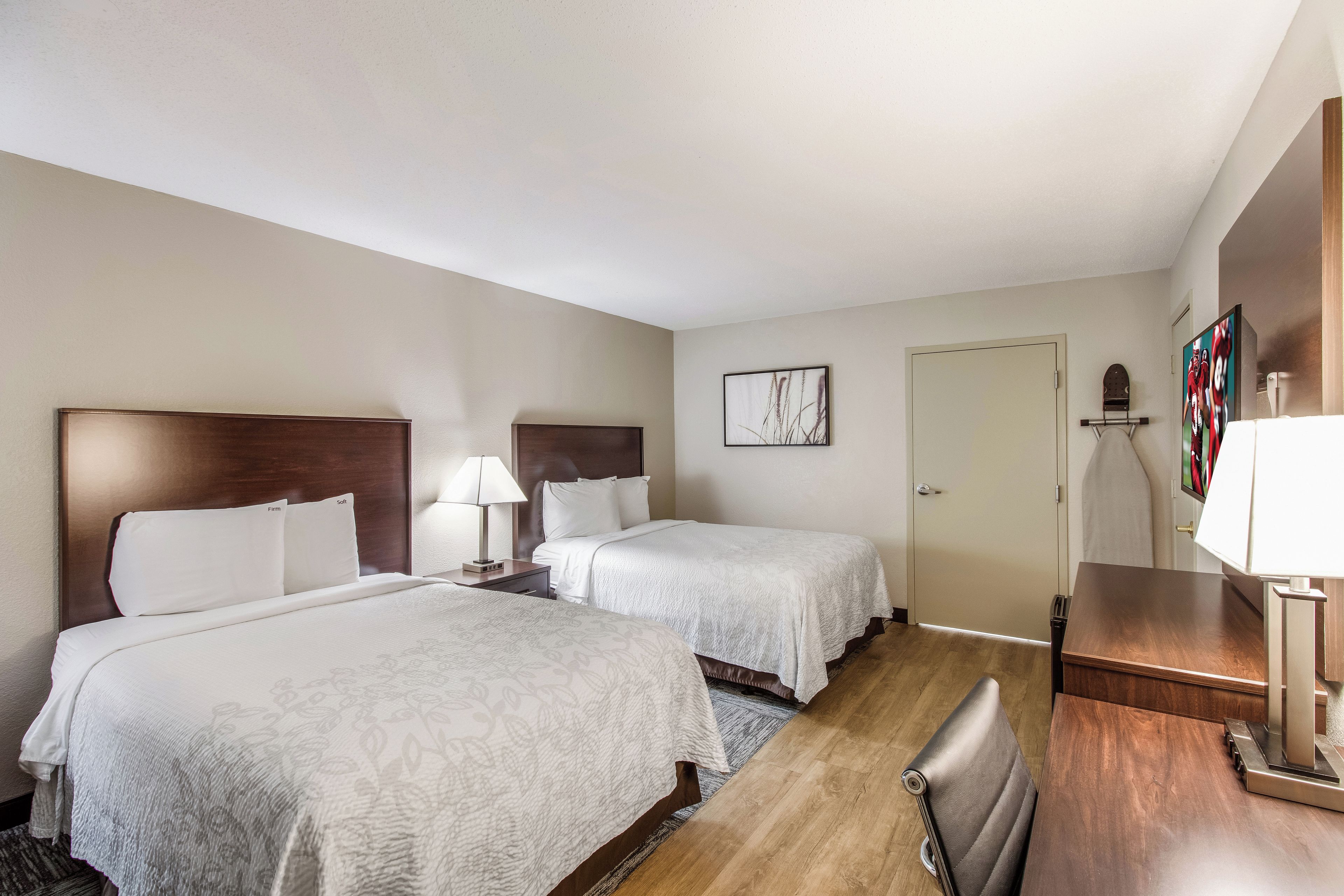 A hotel room with two beds, a desk, and a chair.