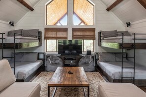 A room with bunk beds, a television, and a coffee table. - Geauxin' All Inn -Gameroom, Bunks, Spacious Covered Deck, Paved Rd, Hot Tub (Broken Bow)