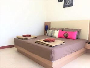 A neatly made bed with two folded towels, a variety of pillows, and a framed artwork on the wall. - OYO 90476 Casa Azlinda Muslim Homestay I (Johor Bahru)