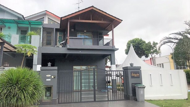 Una casa moderna de dos pisos con balcón, entrada protegida por un portón y un pequeño jardín.