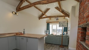 A modern kitchen with a wooden ceiling, grey cabinets, and a wooden countertop. There is a dining area with a sofa and a view of the outdoors. - Shippon (York)