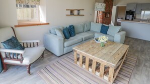 A cozy living room with a light blue sofa, a wooden coffee table, and a patterned rug. - Shippon (York)