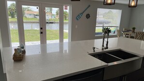 Une cuisine dotée d’un grand îlot central, d’un évier et d’une fenêtre donnant sur un plan d’eau.