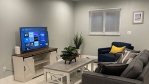 Un salon moderne avec un téléviseur à écran plat, un canapé, une table basse et une plante en pot.
