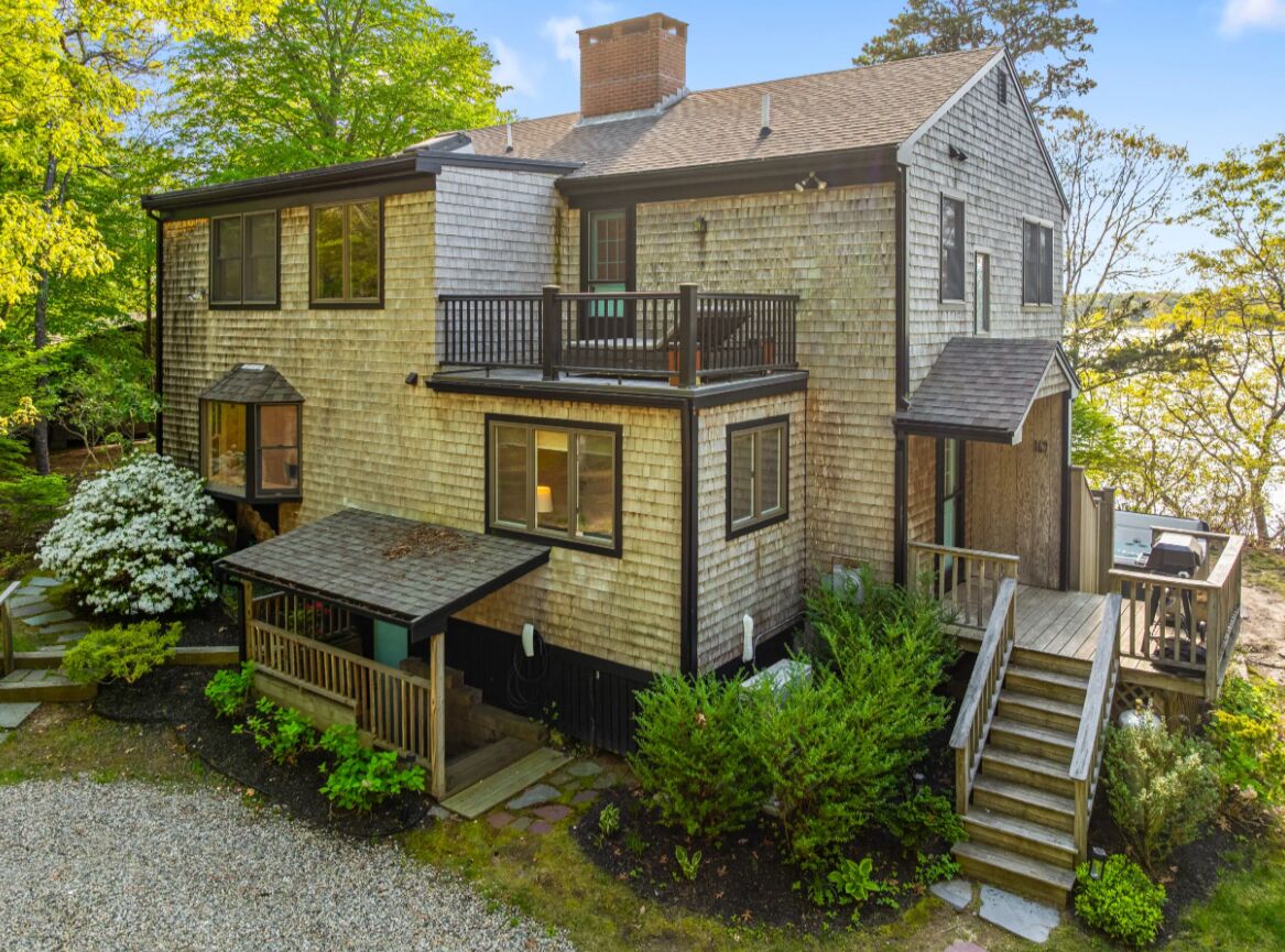 A two-story house with a balcony, a deck, and a staircase leading to a second level.