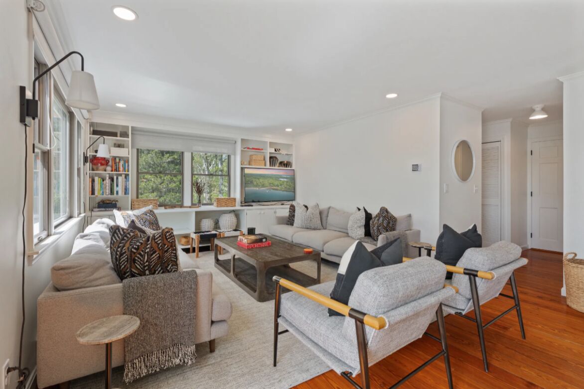 A modern living room with a sofa, armchairs, a coffee table, and a bookshelf.