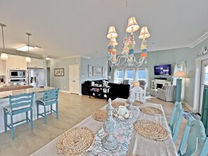 Een ruime woonkamer met een eettafel voor vier personen, een keuken met moderne apparatuur, en een gezellige zithoek met een open haard.