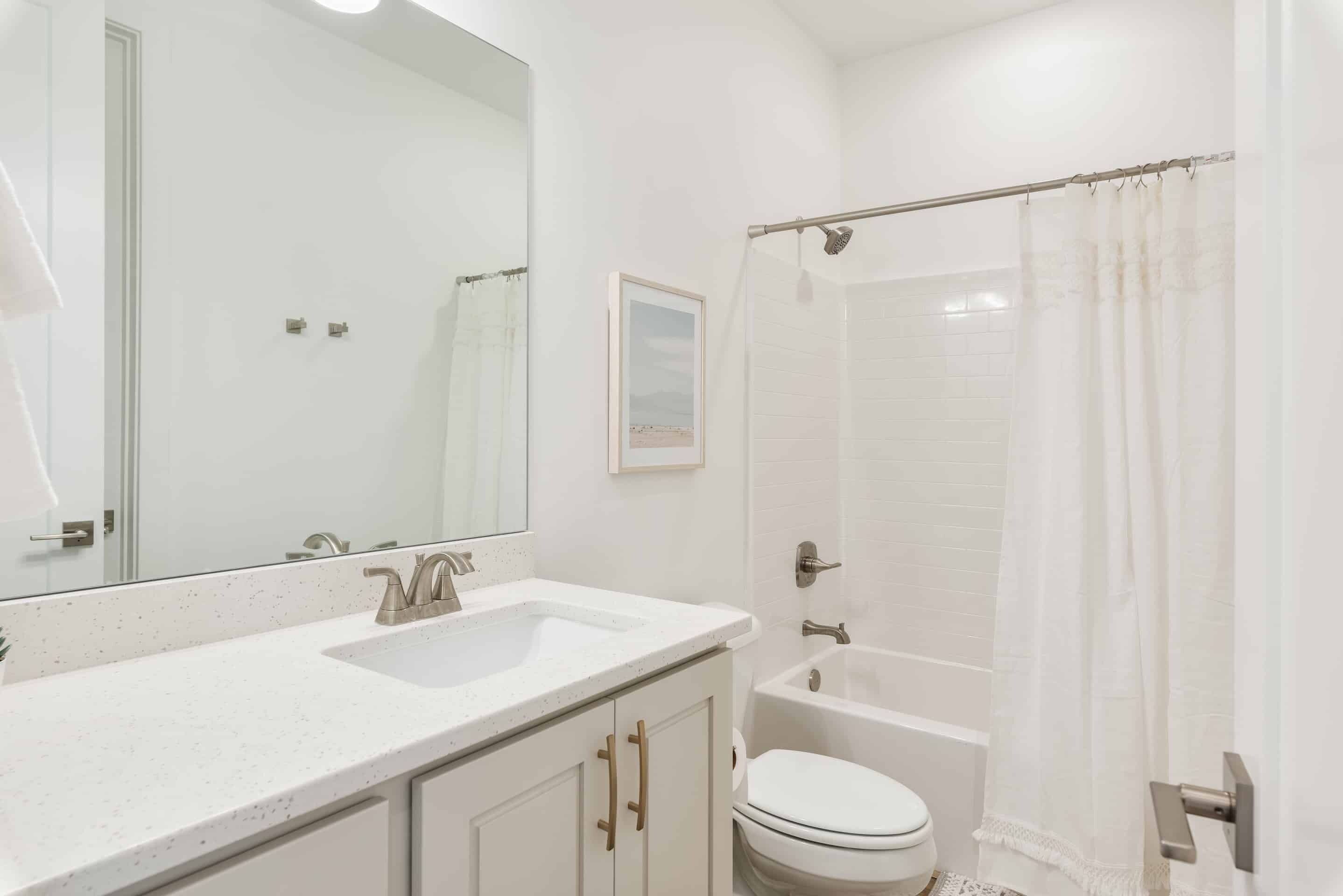 A bathroom with a white sink, mirror, toilet, and shower.