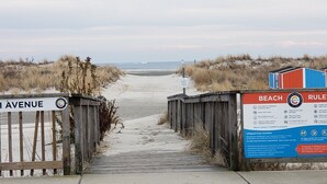 A beach entrance with a wooden boardwalk leading to the beach, a sign indicating 'Miami Avenue', and a 'Beach Rules' sign with guidelines. - Beachfront with Ocean Views right from your balcony (Wildwood Crest)