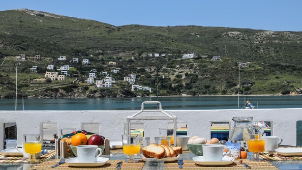 Una mesa con alimentos para el desayuno y una vista panorámica de una colina con casas.