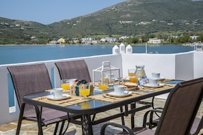 A table set for breakfast with a view of a lake and hills in the background.