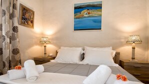Habitación de hotel con cama, dos lámparas de noche, un cuadro en la pared y una ventana con cortinas.