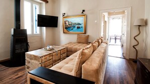 Una sala de estar acogedora con un sofá, un aparador de madera, una chimenea, un televisor y un cuadro en la pared.