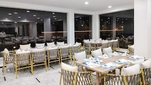 A conference room with multiple tables and chairs, large windows, and a modern interior design.