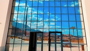 A large window with a grid pattern reflecting a clear sky and distant landscape.