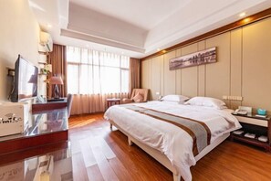 A hotel room with a large bed, a desk with a computer, a chair, and a TV. - Yunchao International Hotel Danzhou (Danzhou)