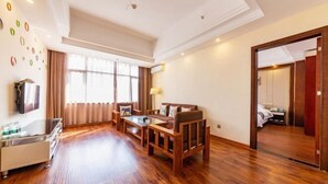 A spacious living room with a sofa set, a coffee table, and a TV on a glass cabinet. - Yunchao International Hotel Danzhou (Danzhou)