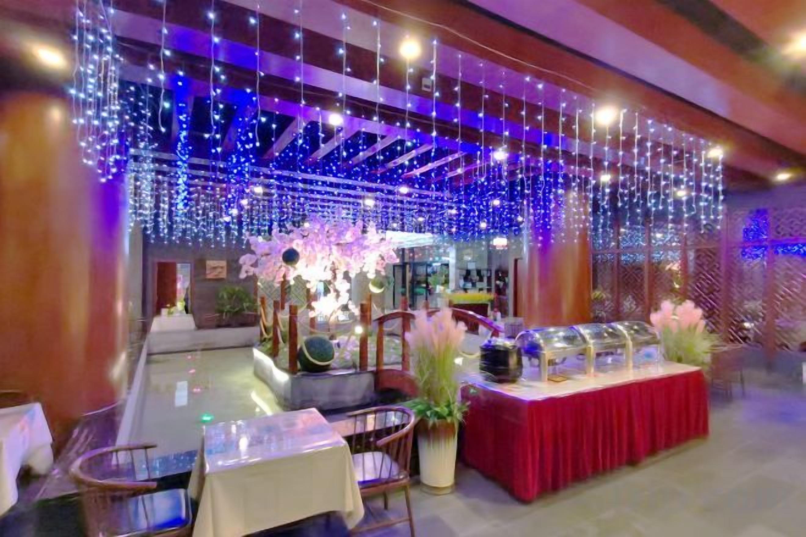 A restaurant with a buffet setup, tables, chairs, and a decorative ceiling.
