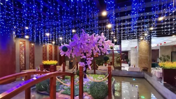 A hotel lobby with a central water feature, a wooden bridge, and hanging blue lights. - Yunchao International Hotel Danzhou (Danzhou)