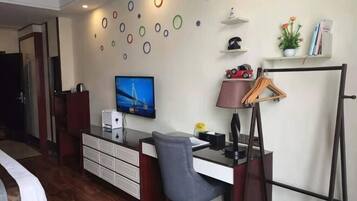 Una habitación de hotel con una cama, un escritorio con una silla, un televisor, una lámpara de escritorio, un perchero y una pared decorada con adornos circulares.