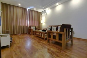 Una sala de estar con piso de madera, un conjunto de sofá, una mesa de centro y una lámpara.