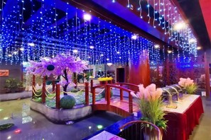 Un espacio interior decorado con una fuente de agua, un puente y una mesa con mantel rojo.