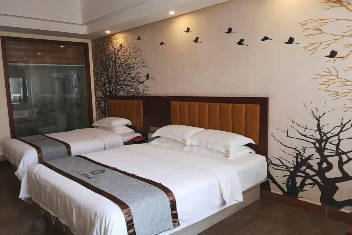 Een hotelkamer met twee bedden, een groot raam en een muurschildering van vogels en bomen.