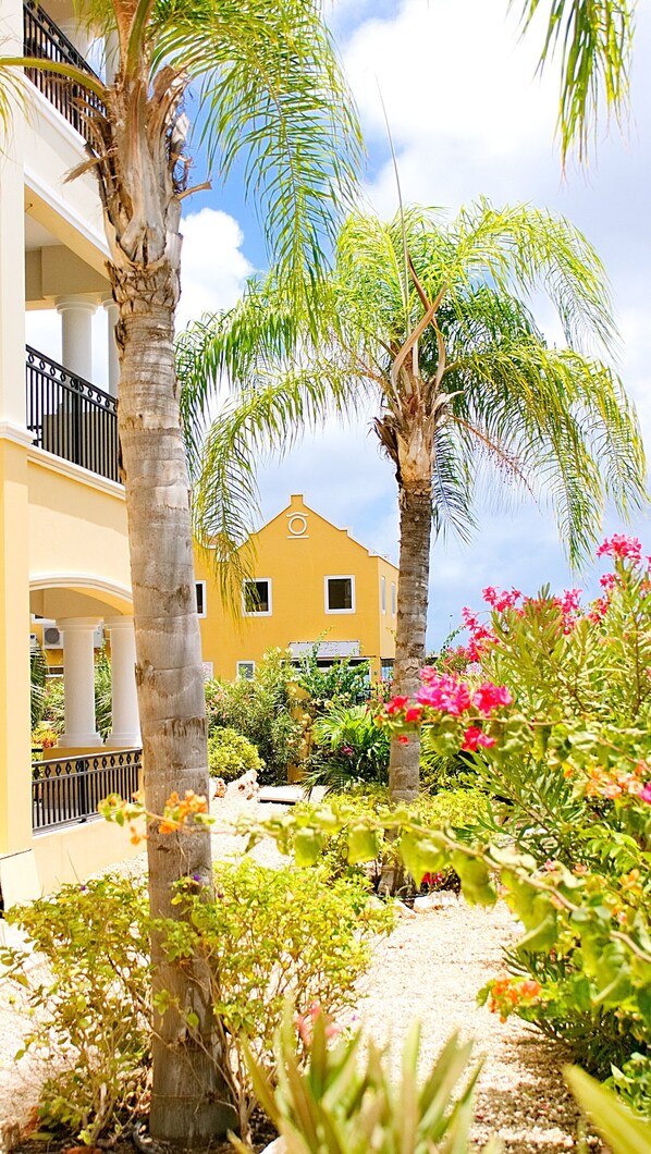 A building with a yellow facade, white columns, and balconies with black railings.